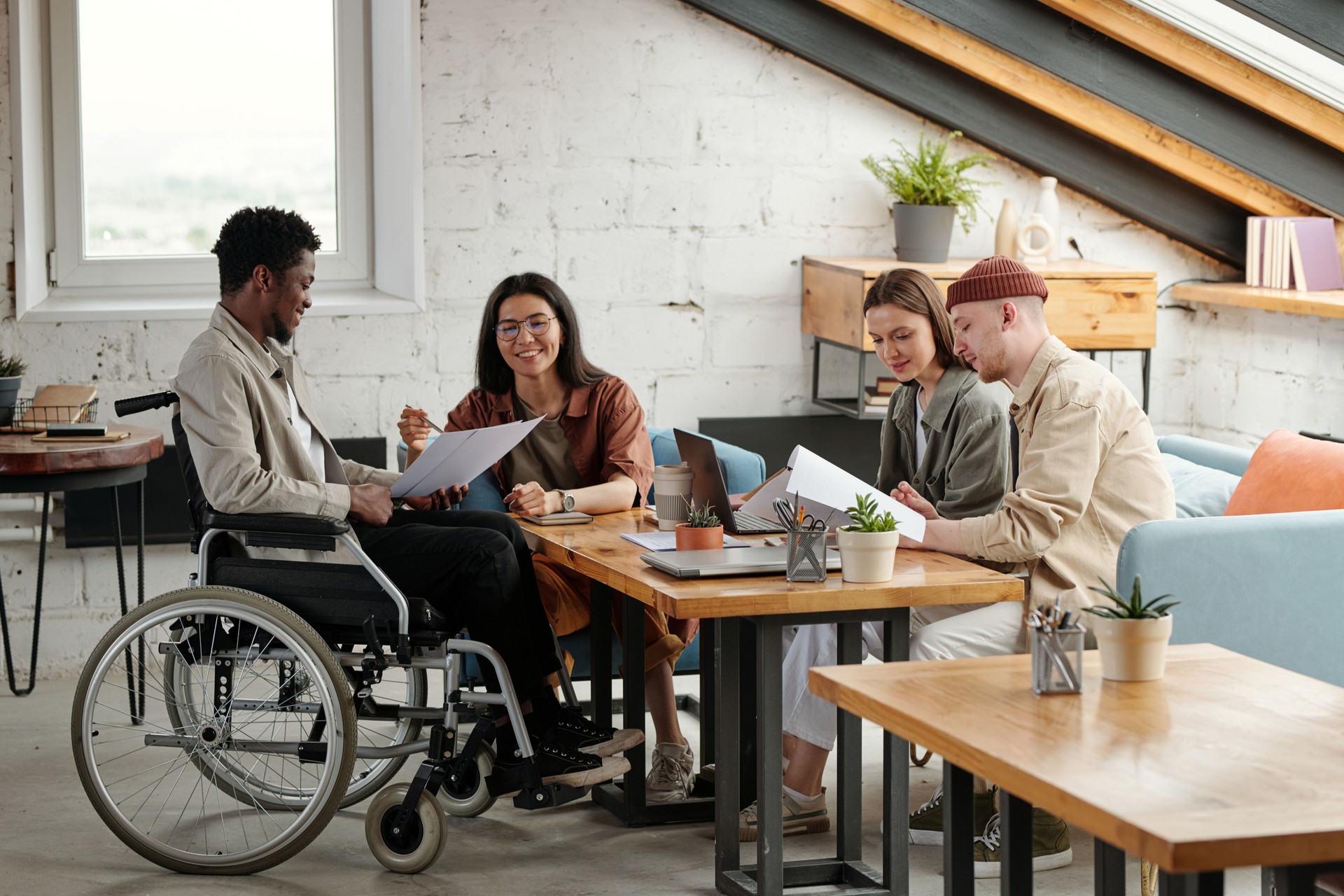 Two pairs of intercultural employees working in small groups by workplace